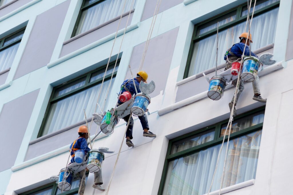 Professional painters masking windows before commercial paint